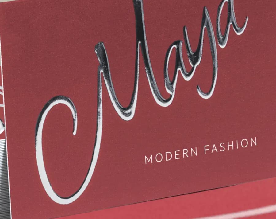 A dark red business card with the name Maya in raised silver foil script.